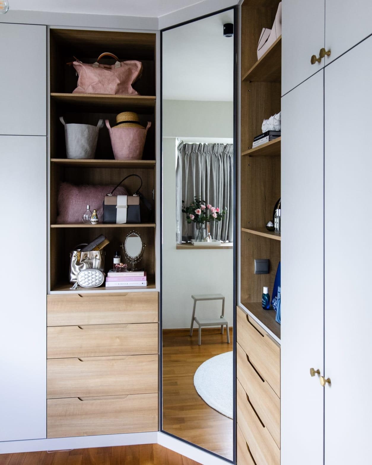 A walk-in wardrobe in a Newton condominium, with open oak shelving set between white lacquer fronts and a mirrored corner returning the window into the room.