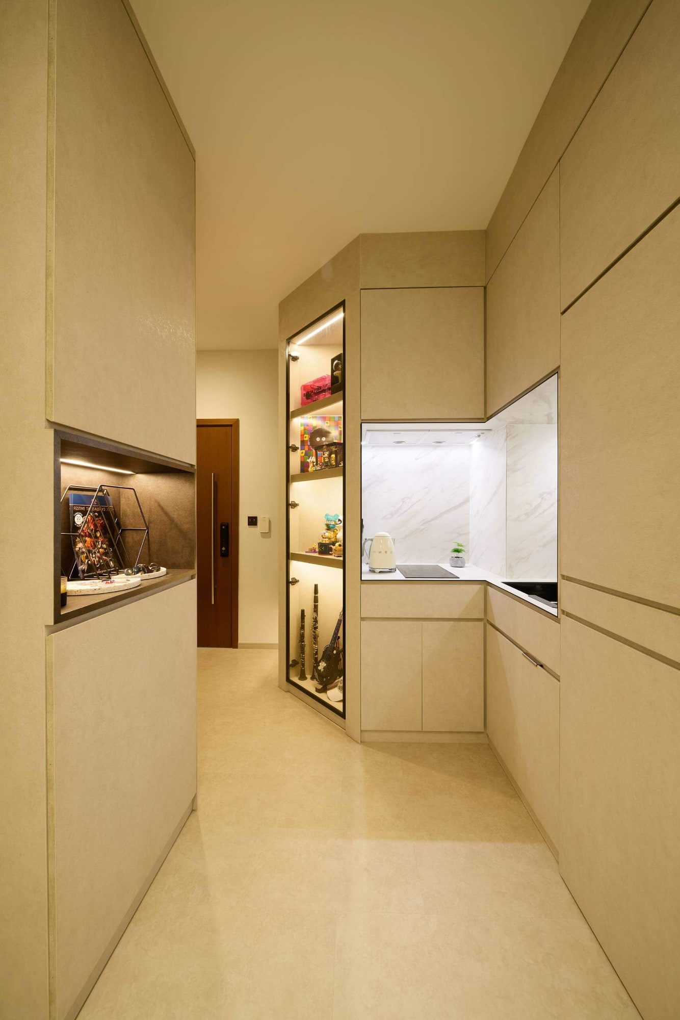 The joinery corridor seen from the entrance, with glazed display cases lit from within and a marble-lined kitchen recess.