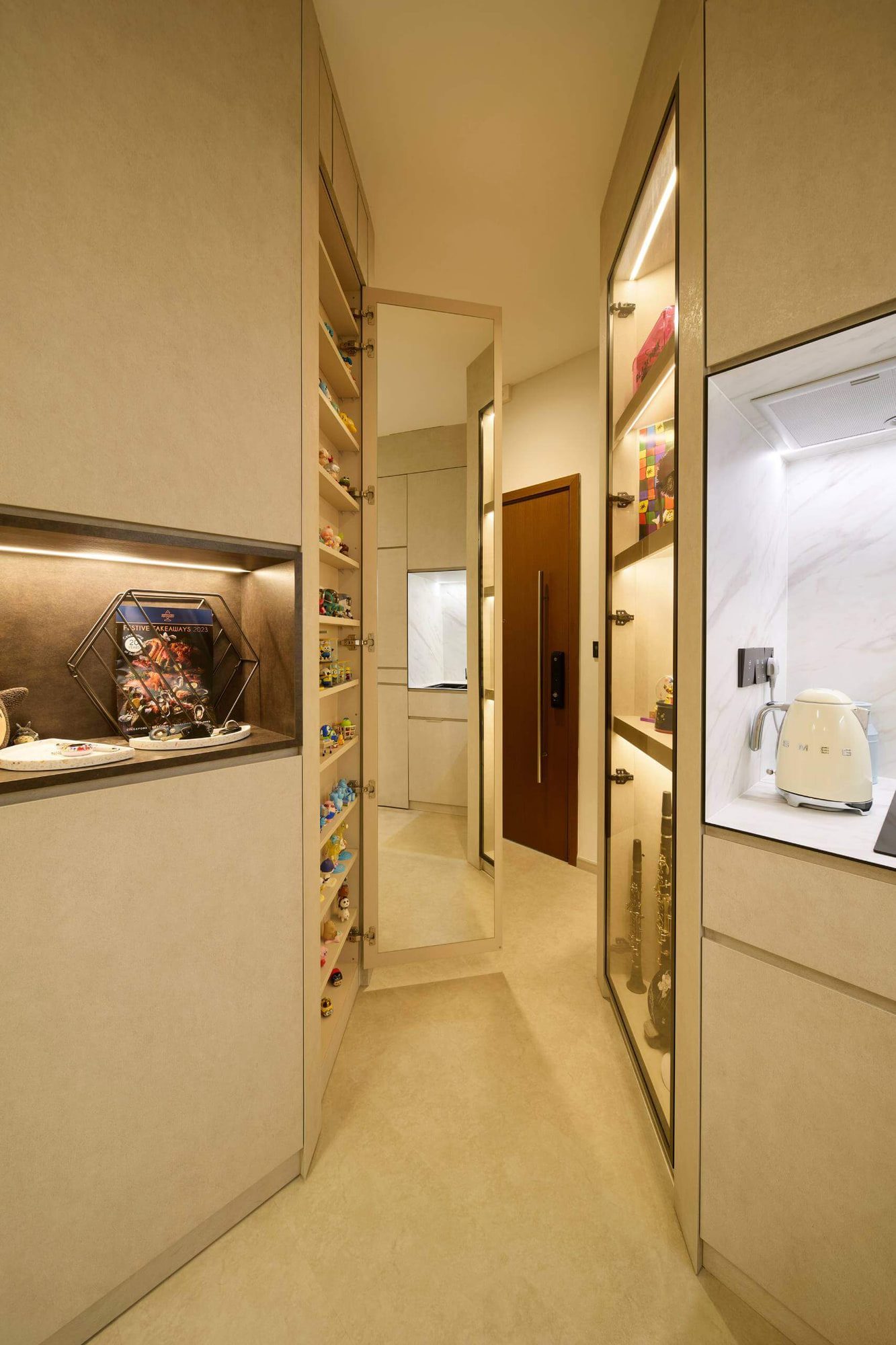 Glazed display cabinets running the length of the hall, mirrored at the return, with a compact kitchen beyond.